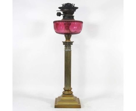 A 19th century brass oil lamp, in the form of a Corinthian column, with a cranberry glass reservoir, stamped Young's, with a 