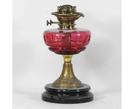 An early 20th century brass oil lamp, with a cranberry glass star cut font, 34cm highOverall condition looks to be complete b