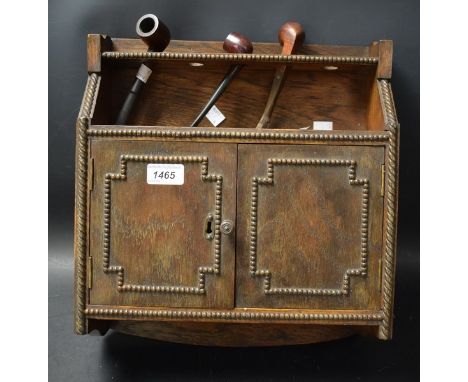 An Oak two door smokers cabinet, fitted interior with three pipes, one with silver fittings