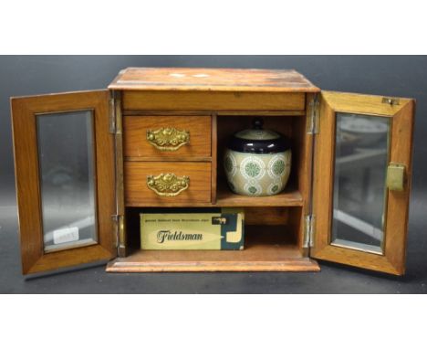 An Edwardian oak two door smokers cabinet, glazed doors, fitted interior, with Meerschaum pipe and mixing bowl