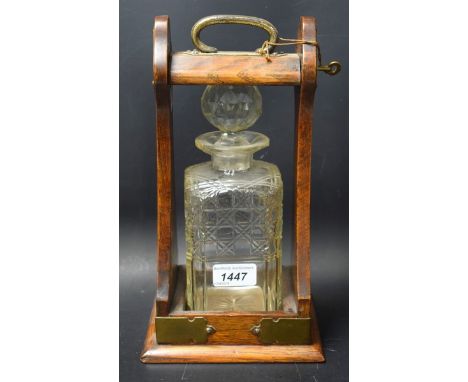 An oak single decanter tantalus, brass fitting with key