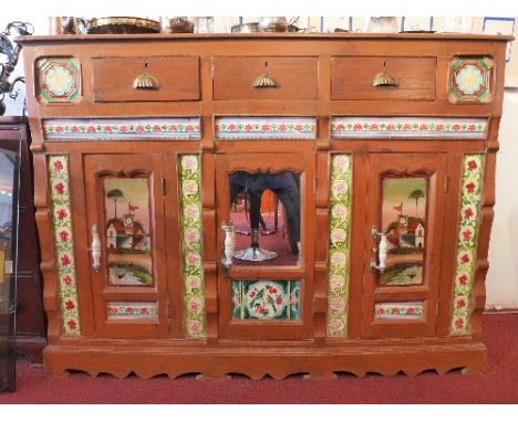 A 20th Century Indonesian teak sideboard having three drawers above three doors with glass panels and inset with ceramic tile