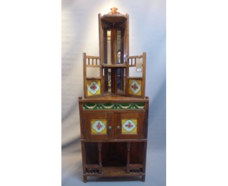 A 20th Century teak corner unit inset with floral ceramic tiles and mirrored back, H:177cm W:63cm D:26cm