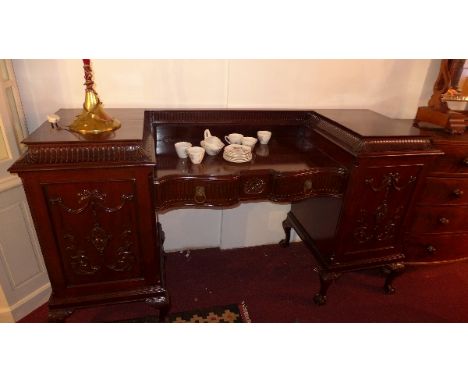 A 1920's Chippendale style mahogany sideboard with central secret drawer flanked by two drawers and two cupboard raised on ba
