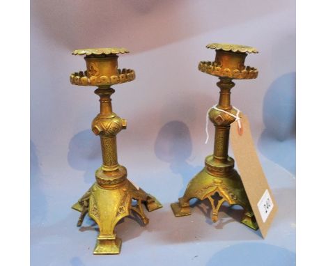 Two Middle Eastern brass candlesticks, with floral decoration, raised on tripod bracket feet, H. 19cm (2)
