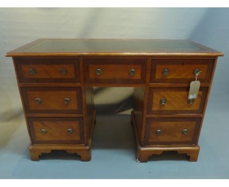 A 20th Century satinwood and rosewood kneehole desk having seven drawers raised on carved bracket base, H:89cm W:124cm D:56cm