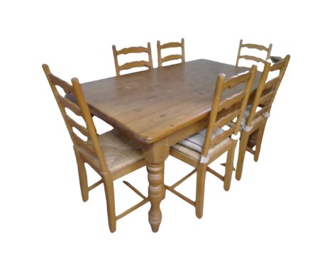 A pine farmhouse dining table with six ladder backed chairs, table length 153 cm