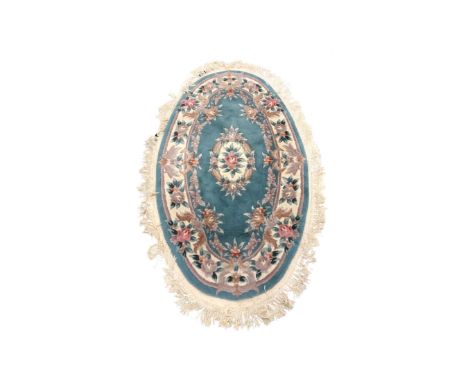 A Chinese embossed oval fringed rug on light blue ground, length 182 cm