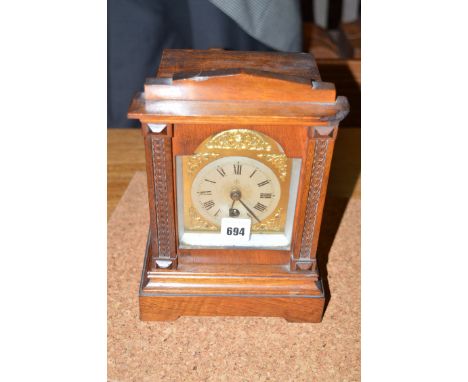 A Victorian mantel clock in walnut case, with decorative carved columns flanking the arched dial.
