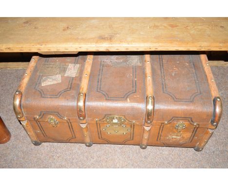 An early 20th Century wooden metal bound canvas covered trunk with brass clasps and leather carrying handles.