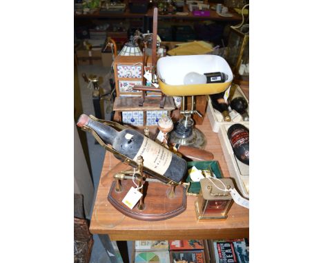 A carriage clock; a bottle stand; an old bottle; a reproduction desk lamp; two wood and ceramic spice cabinets; a radio; a Ti