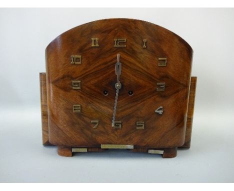 AN ART DECO MANTEL CLOCK, with applied relief Arabic numerals to walnut veneered case and silvered hands, dome top and bracke