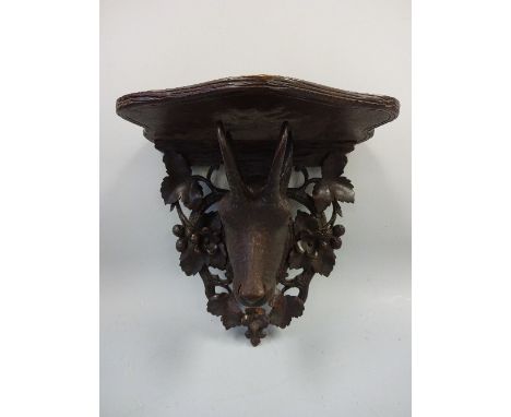 A BLACK FOREST CARVED WALL BRACKET, the demi lune shelf supported on carved and  pierced oak leaf and acorn back plate with f