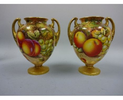 A PAIR OF ROYAL WORCESTER TWO HANDLED URN VASES, on circular footed bases, ovoid body hand painted with peaches, grapes and a