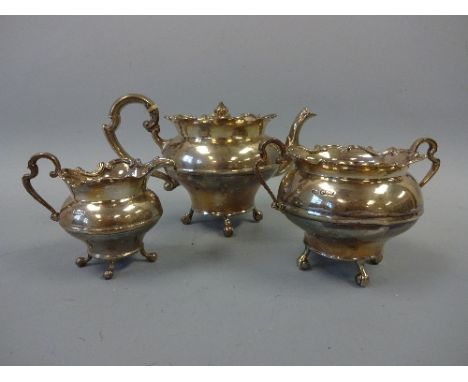 A SILVER THREE PIECE TEA SERVICE, of waisted form with shaped tops set on scroll feet, teapot approximately 12cm high, Sheffi