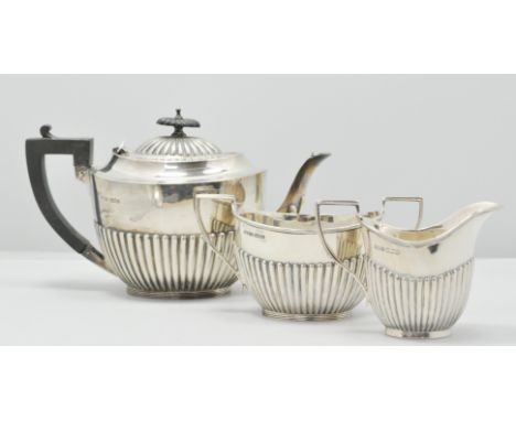 Matched three-piece silver teaset, Sheffield 1924-25, semi-fluted oval form, the teapot with ebonised handle and finial, 17cm