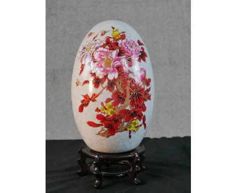 A large Chinese transfer printed and gilded floral and insect design crackle glaze ceramic egg, gilded characters to the reve