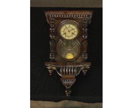 A Victorian walnut cased regulator wall clock, with Roman numerals to the enamelled chapter ring, the case with turned and be