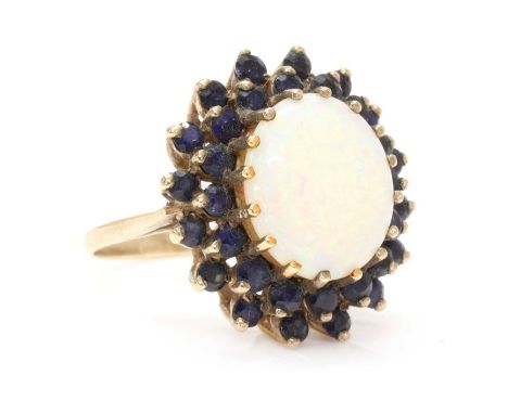 A 9ct gold opal and sapphire cluster ring, an oval cabochon opal, approximately 14 x 12mm, claw set, to two row surround of c