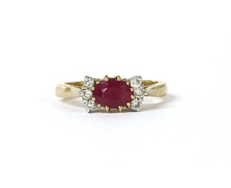 A 9ct gold ruby and diamond ring, with an oval mixed cut ruby, possibly synthetic, set in landscape orientation, with a verti