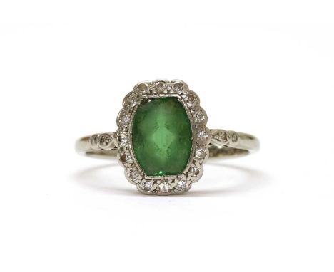 A white gold tourmaline and diamond ring, a cushion cut green tourmaline, chipped, milligrain set to surround of eight cut di