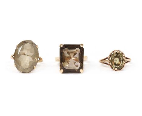 Three single stone smoky quartz rings, to include an emerald cut smoky quartz ring, tested as approximately 9ct gold with lat