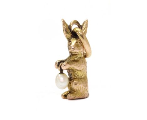 A Continental gold pearl charm, in the form of a rabbit or hare, holding a wire set pearl, with oval jump ring, tested as app