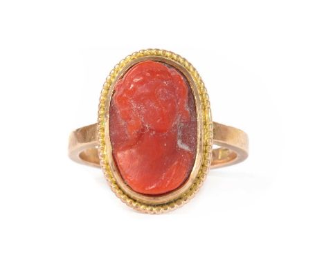 A gold coral cameo ring, the coral cameo rub set to a beaded border, with square section shank, tested as approximately 9ct g