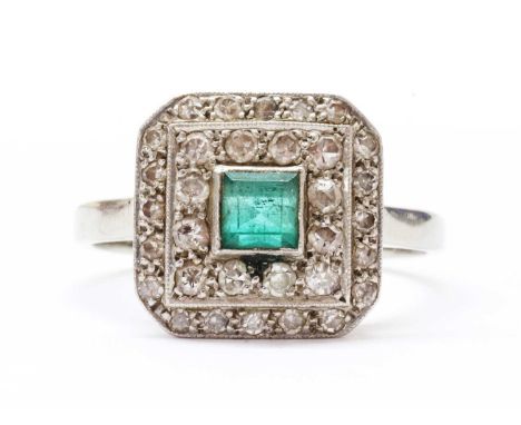 A white gold emerald and diamond cluster ring, with a square step cut emerald, approximately 4mm, milligrain set at the centr