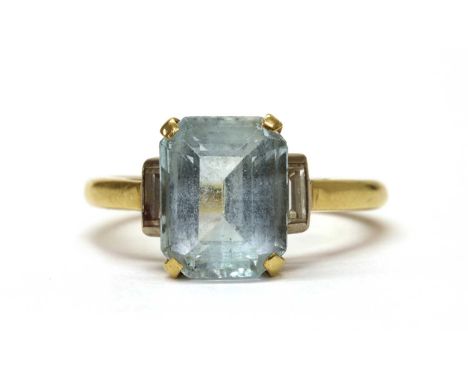 A gold blue topaz and diamond three stone ring, an emerald cut blue topaz, four claw set, with a baguette cut diamond rub set