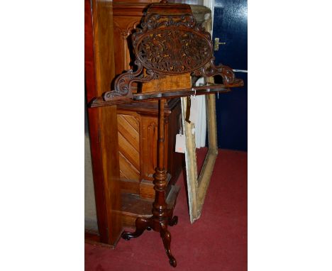 A Victorian walnut and figured walnut music stand, having rise-and-fall action and a fret carved oval panel within scroll lea