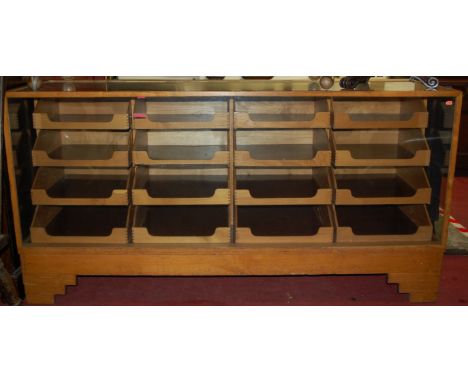An Art Deco light oak and glazed haberdashery cabinet, fitted with 16 graduated drawers, on stepped supports, w.178cm 
