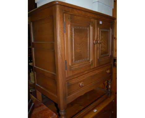 An Ercol light elm double door side cupboard, of small proportions, having single lower drawer