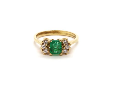 An 18ct yellow gold (tested) emerald and diamond ring, emerald has natural inclusions, diamonds bright and lively, head size 