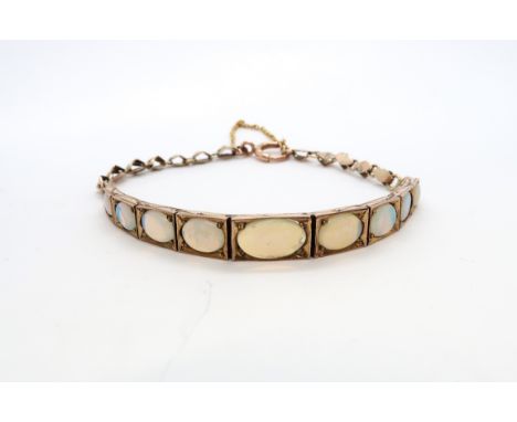 A 9ct yellow gold and opal articulated bracelet with nine graduated opals - 7.1 grams 