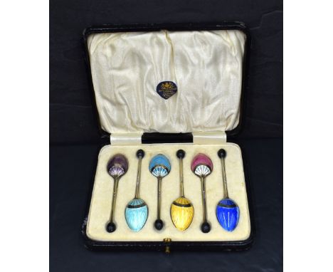 A cased set of George V coffee bean spoons having an Art Deco guilloch enamel design to the reverse and coffee bean at the te