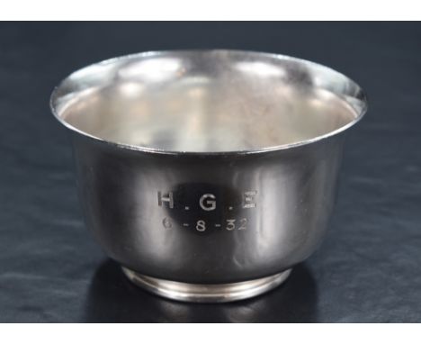 A George V silver sugar bowl of circular form, having a flared rim and plain body raised on a moulded circular foot, engraved