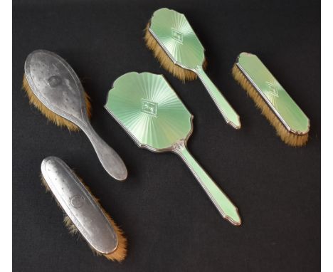 A George V three-piece silver and green guilloch enamel dressing table set, comprising a clothes brush, hair brush and a mirr