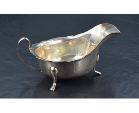 A George VI silver sauce boat of traditional design, with Chippendale style rim, generous spout opposed by a loop handle rais