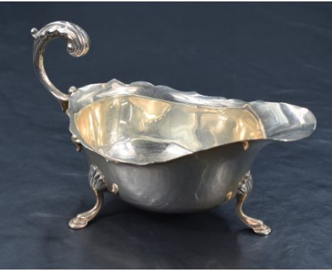 A George V silver sauce or gravy boat, with Chippendale style rim, generous spout opposed by a decorative scrolling handle, r