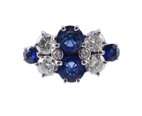 A SAPPHIRE AND DIAMOND RING  LONDON 1990 The marquise shaped panel with a central pair of claw set circular cut sapphires, fl