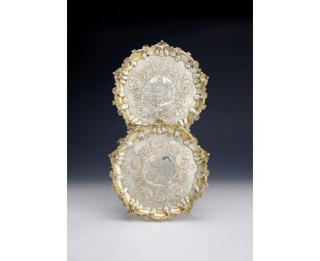 A PAIR OF GEORGE III SILVER GILT SALVERS WILLIAM PITTS, LONDON 1778 With raised shell and scroll borders, later chased with C