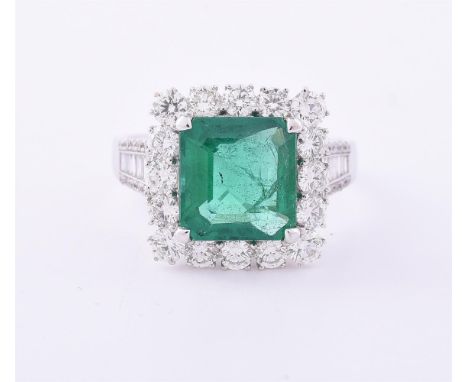 AN EMERALD AND DIAMOND CLUSTER RING The step cut emerald with canted corners estimated to weigh 2.46 carats, within a surroun