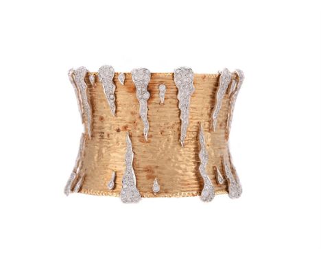 A DIAMOND AND GOLD COLOURED CUFF BANGLE  The broad textured shaped clasp with applied tapering and undulating brilliant cut d