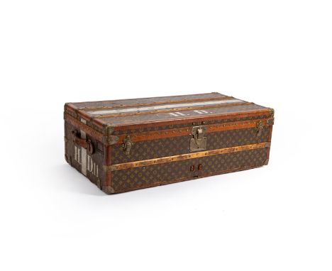 LOUIS VUITTON  A MONOGRAMMED COATED CANVAS HARD TRAVELLING TRUNK, 20TH CENTURY With leather and brass trim, wood slats, two l