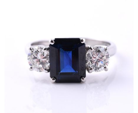 A DIAMOND AND SAPPHIRE THREE STONE RING The central step cut sapphire with canted corners, flanked between two brilliant cut 