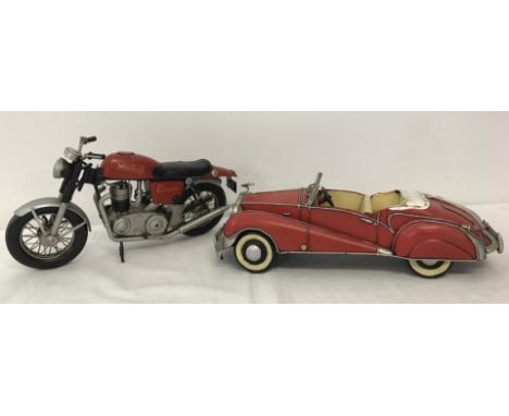 A vintage tin plate Norton motorcycle together with a Rolls Royce convertible, both in red colours.  