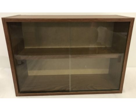 A wood effect wall hanging display cabinet. With interior shelf and 2 sliding glass doors. 32cm tall x 46.5 wide.