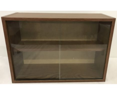 A wood effect wall hanging display cabinet. With interior shelf and 2 sliding glass doors. 32cm tall x 46.5 wide.