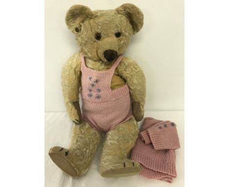 A c1930's blond haired Chad Valley jointed Teddy Bear with knitted outfit. Button in ear. Replacement pads on hands and feet.